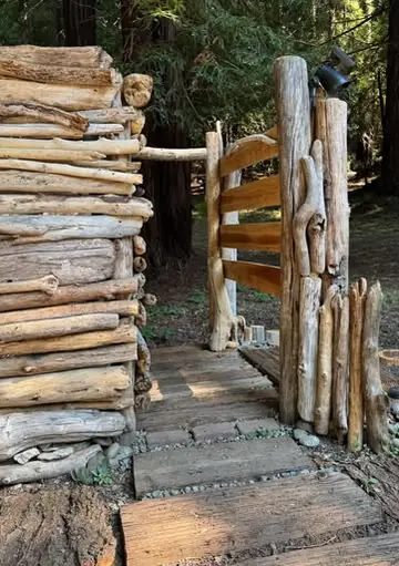 A rustic gate and wall built from stacked branches and logs